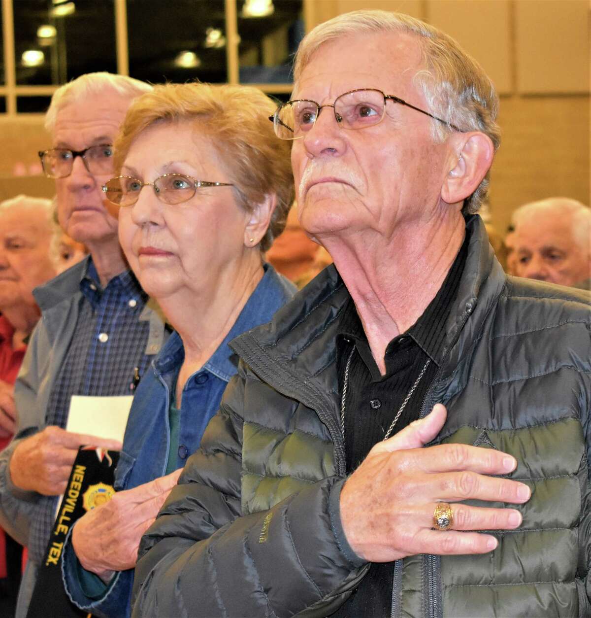 Saluting the American flag during "The National Anthem" at Needville High School's Veterans Day program on Friday are, from left, Army veteran Raymond Schmidt and his wife Evelyn, and Army veteran Julius Maresh.