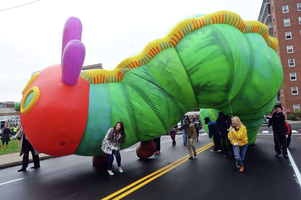 Volunteers Kaitlyn Florio of Norwalk, left, and Michele Hall of Stamford, right in yellow, attempt to lower the 35-foot long inflatable Very Hungry Caterpillar balloon under a wire while practice for the 2017 Stamford Downtown Parade Spectacular on Walton Place in downtown Stamford, Conn. on Monday, Nov. 13, 2017.