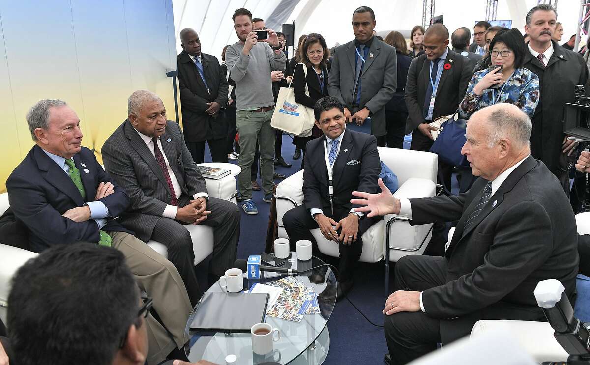 Former New York Mayor and billionaire Michael Bloomberg, left, speaks with Fiji prime minister and COP president Frank Bainimarama, beside him, and California Governor Jerry Brown, right, in the U.S. Climate Action Center at the COP 23 Fiji UN Climate Change Conference in Bonn, Germany, Saturday, Nov. 11, 2017. Bloomberg's "America's Pledge" campaign works to compile and tally the climate actions of states, cities, colleges, businesses, and other local actors across the entire U.S. economy. (AP Photo/Martin Meissner)