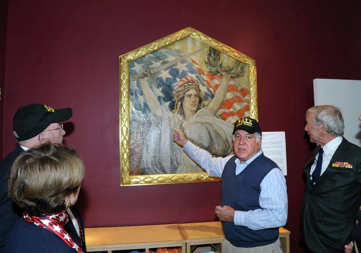 Second from right, Greenwich resident Dean Gamanos, a Navy veteran, discusses the George Wharton Edwards oil on canvas 1918 painting, "Miss Liberty," as part of the Greenwich Veterans Day activities at the Bruce Museum in Greenwich on Saturday. The painting belongs to American Legion Post 29 in Glenville and is temporarily on loan to the museum and can be seen in the museum's lobby area.
