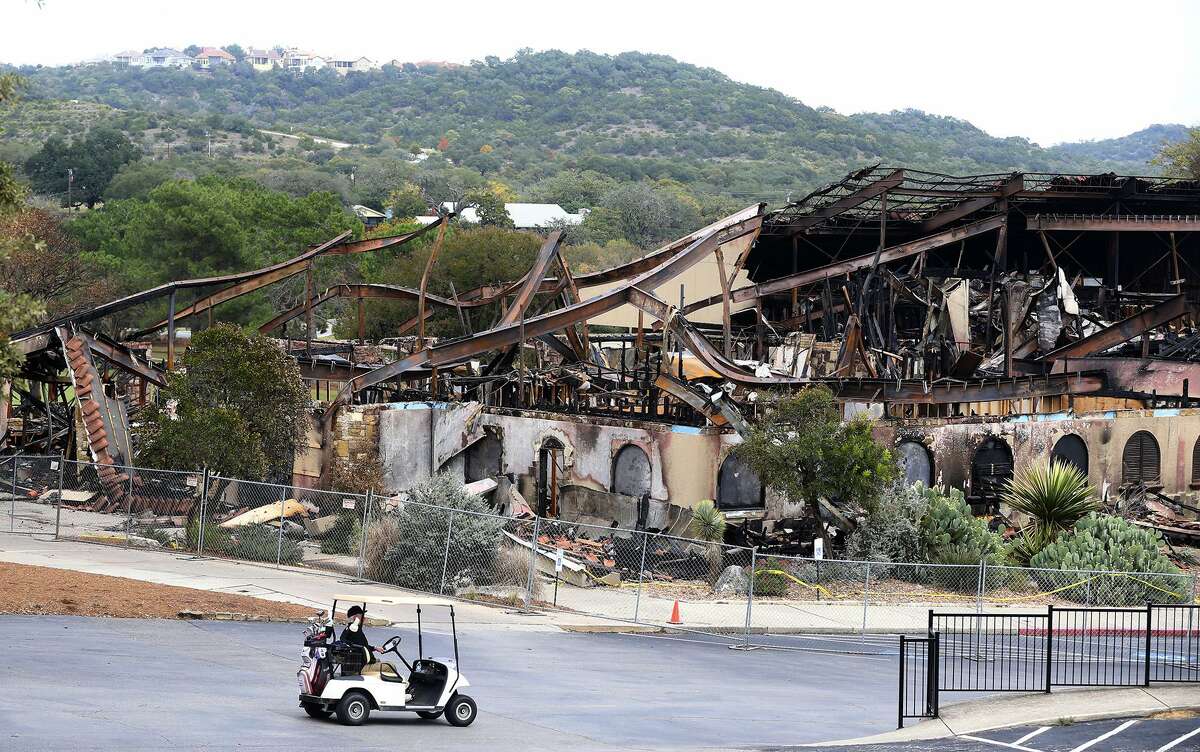 A man driving a golf cart passes the burned club house at the Tapatio Springs Hill Country resort near Boerne, Texas. A fire destroyed the building Saturday night November 4, 2017. Tapatio Springs is on 220 acres in the Hill Country. Its 18-hole golf course recently underwent a $2 million renovation. One of its owners is country music star George Strait.