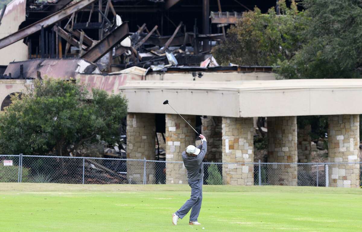 A man golfs in front of the burned club house at the Tapatio Springs Hill Country resort near Boerne, Texas. A fire destroyed the building Saturday night November 4, 2017. Tapatio Springs is on 220 acres in the Hill Country. Its 18-hole golf course recently underwent a $2 million renovation. One of its owners is country music star George Strait.