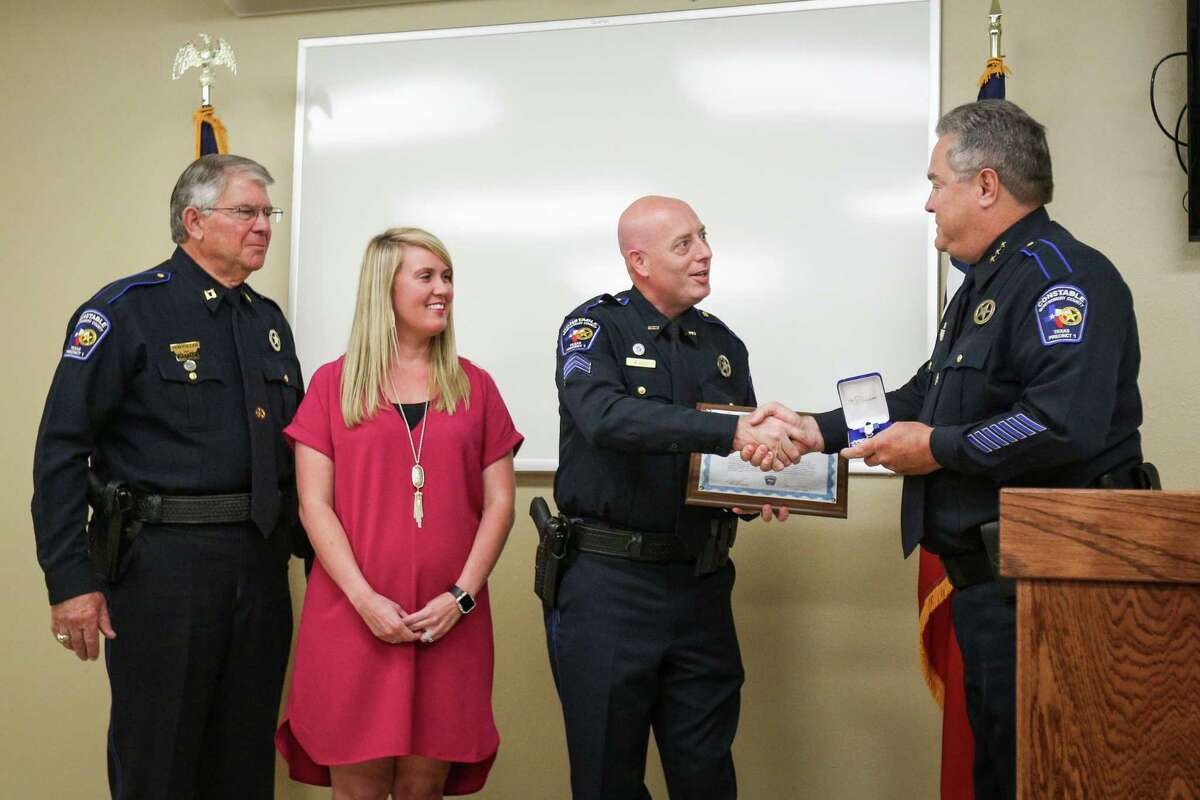 Precinct 1 Constable Philip Cash, right, shakes hands with deputy Brian Luly, center right, who was accompanied by his wife Ashley Luly, center left, and Cpt. Don Fullen, left, during a certificate of valor presentation on Monday, Nov. 13, 2017, at Precinct 1 Constable's Office.