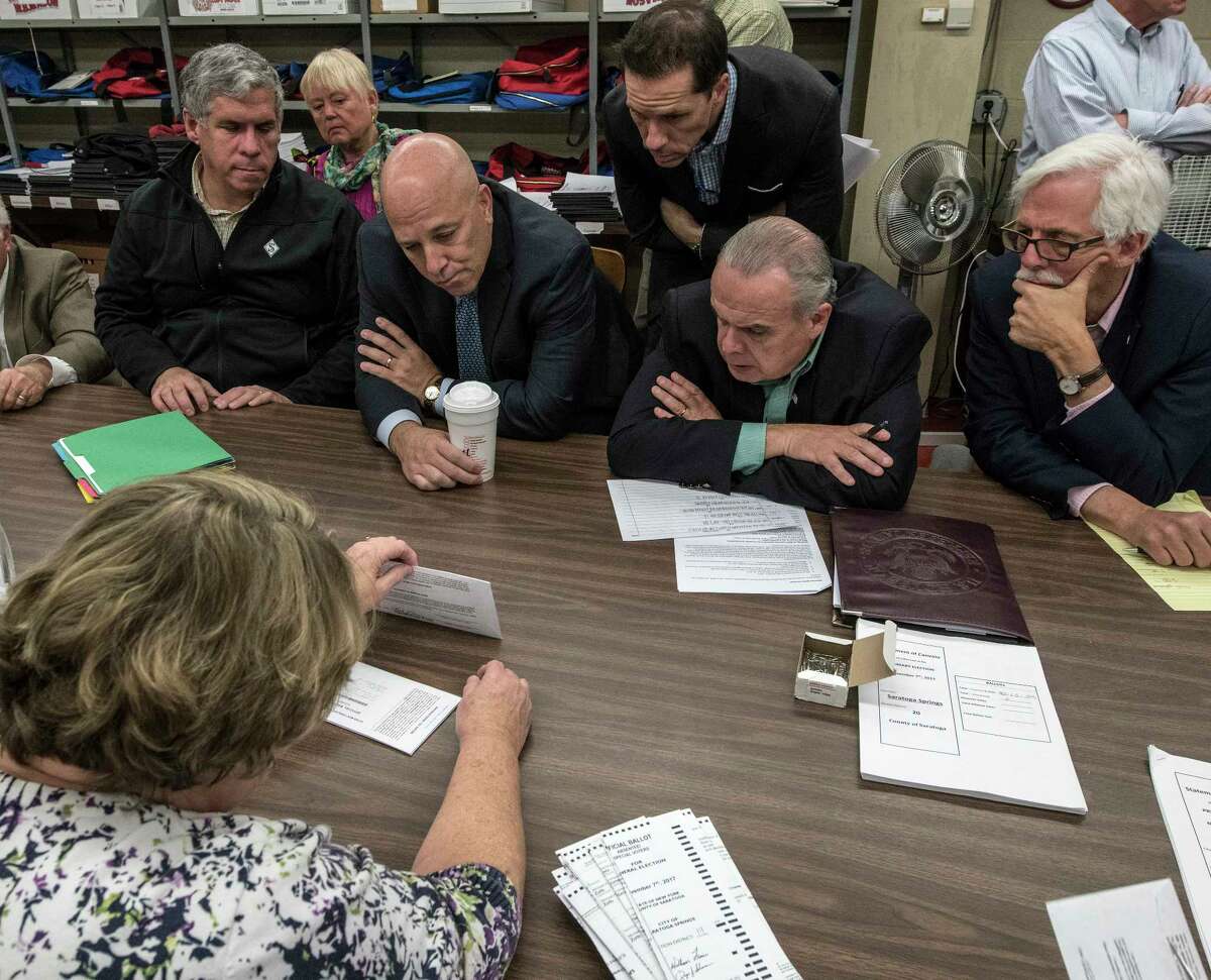 Representatives from the Democrats and the Republicans huddle up over the recount of absentee ballots in the City of Saratoga election as they look closely at the City Charter vote and the race for the Public Safety Commissioner Tuesday Nov. 14, 2017 at the Saratoga County Board of Elections offices in Ballston Spa, N.Y. (Skip Dickstein/ Times Union)