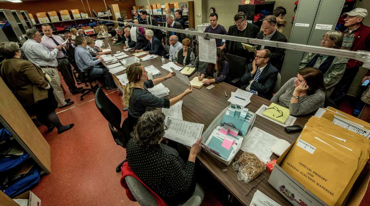 Representatives from the Democrats and the Republicans huddle up over the recount of absentee ballots in the City of Saratoga election as they look closely at the City Charter vote and the race for the Public Safety Commissioner Tuesday Nov. 14, 2017 at the Saratoga County Board of Elections offices in Ballston Spa, N.Y. (Skip Dickstein/ Times Union)