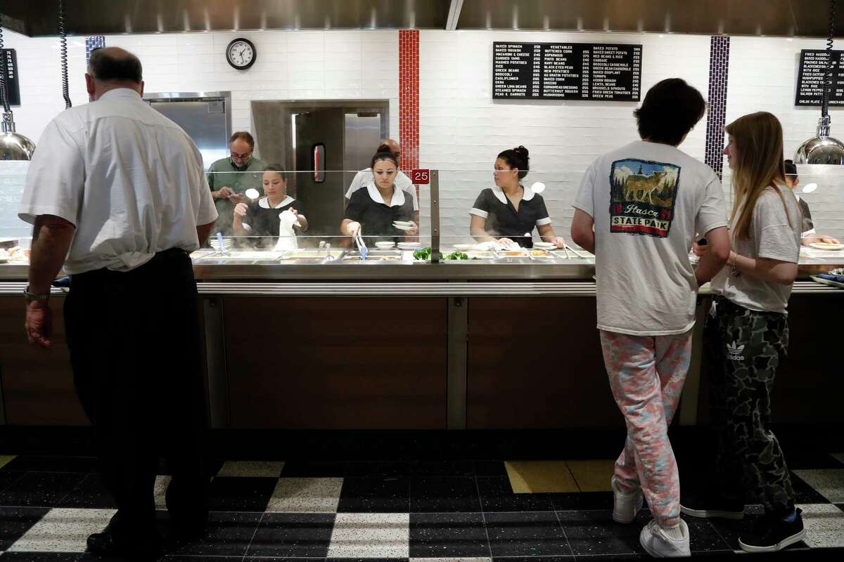 Cleburne Cafeteria servers dish out food to a long line of customers during their soft opening, Tuesday, Nov. 14, 2017, in Houston. Cleburne Cafeteria, which was destroyed by fire in 2016, now features several upgrades including a patio, the ability to order wine and beer and some menu additions.