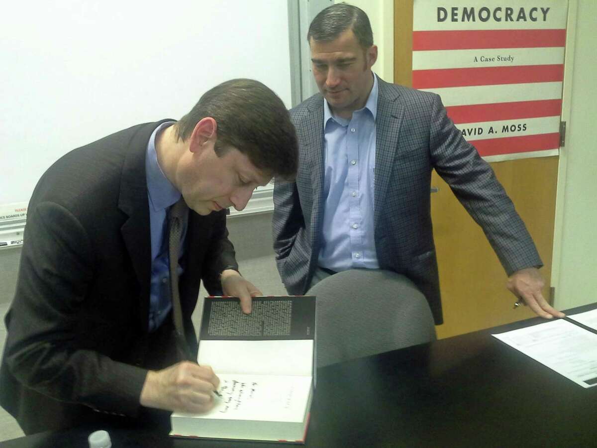 Harvard professor David Moss signs a copy of his book “Democracy: A Case Study” for GHS U.S. History teacher Michael Gailatioto at the high school Tuesday.