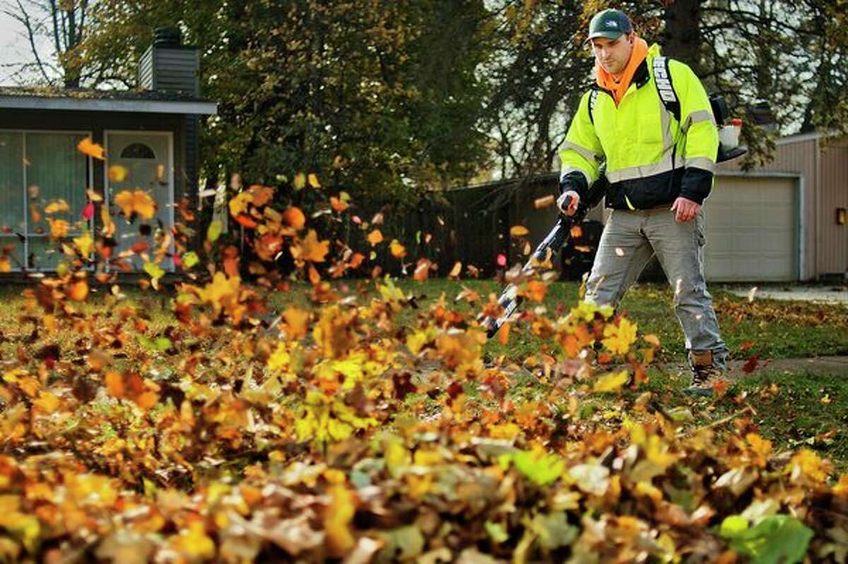 Kris Konechne uses a leaf blower to clear fallen leaves from his front yard on Tuesday in Midland. (Katy Kildee/kkildee@mdn.net)