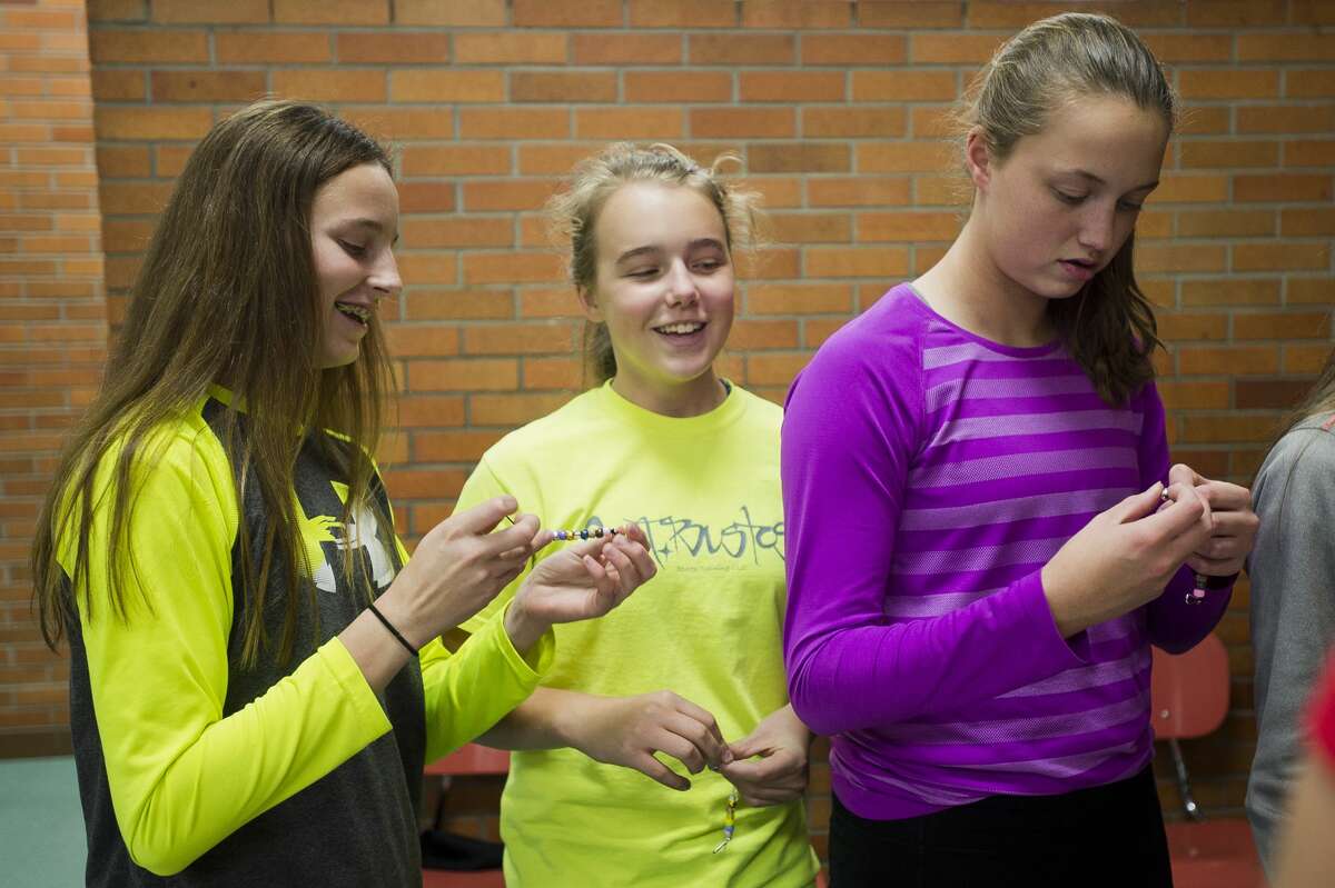 From left, Tristain Luick, 13, Makayla Mann, 12, and Summer Luick, 13, put together beaded keychains that represent their individual genetic traits with the help of volunteers from Dow, during The ROCK, a daily after-school program featuring snacks, tutors, crafts and games, on Wednesday, Nov. 15, 2017 at Jefferson Middle School. (Katy Kildee/kkildee@mdn.net)