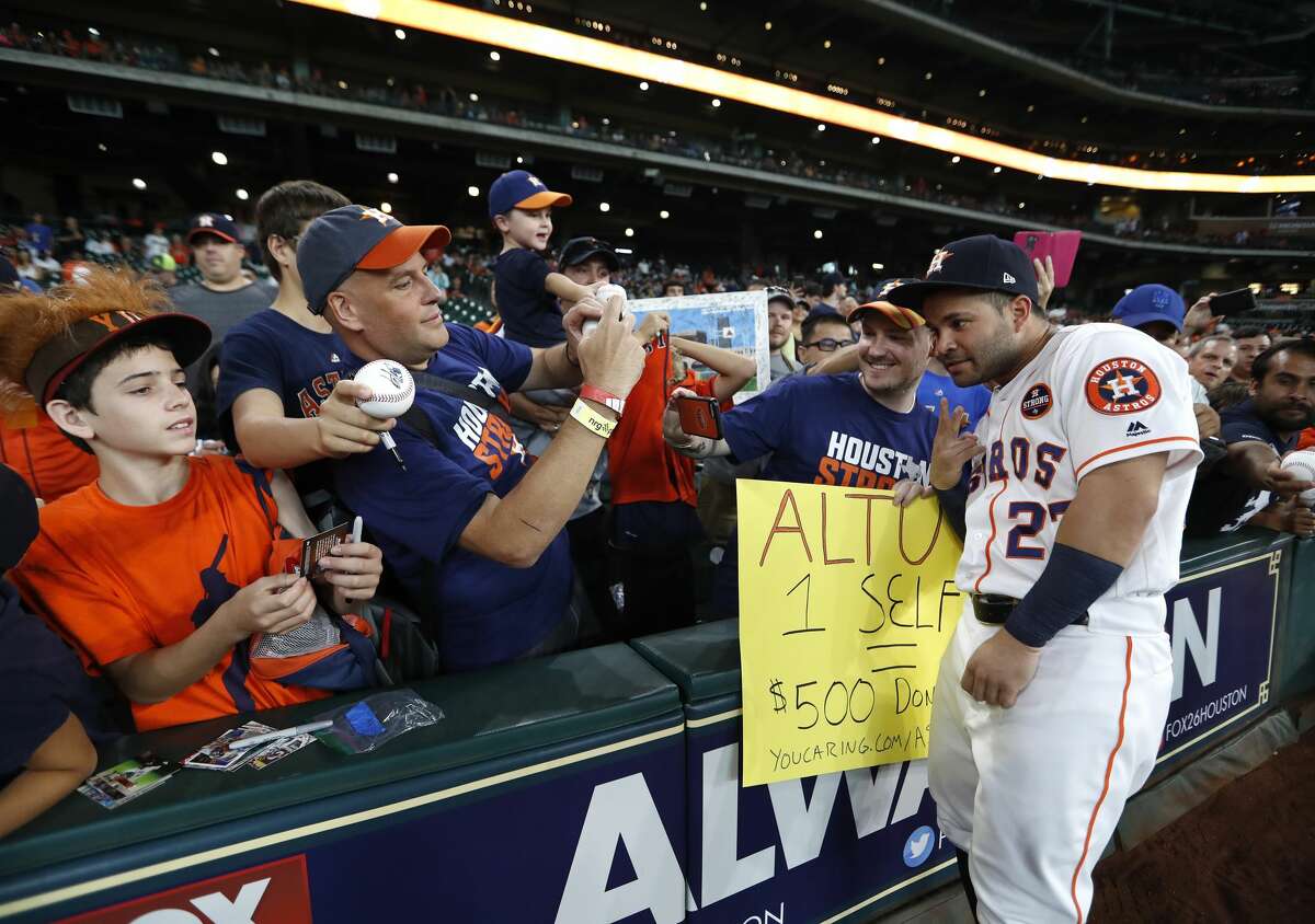 Houston Astros second baseman Jose Altuve (27) takes a selfie with fans who claim they would donate $500 to the Share To Care campaign before the start of an MLB baseball game at Minute Maid Park, Saturday, Sept. 2, 2017, in Houston. This is the first professional sporting event in the city since Tropical Storm Harvey.
