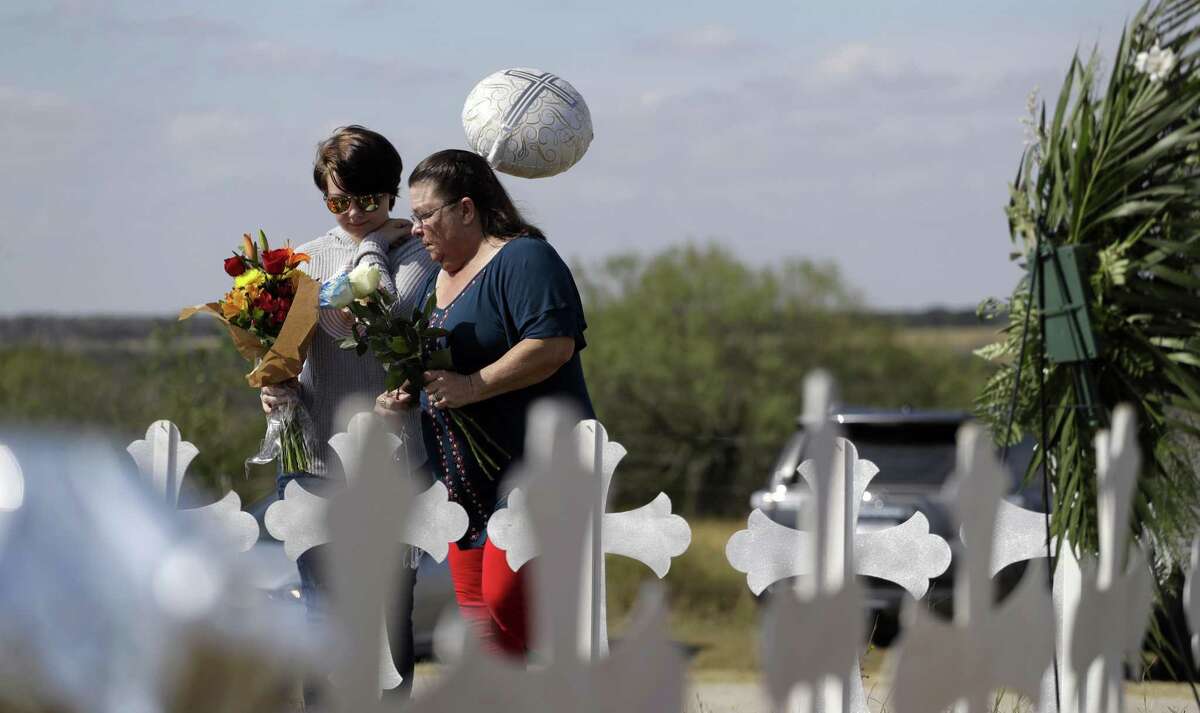 Texas leaders, how many deaths is too many before you acknowledge that the common denominator in mass shootings is the ready availability of guns? Here, Randi Ray Rivera (left) and Belenda McLauren visit a makeshift memorial near the scene of the shooting at the First Baptist Church of Sutherland Springs. Twenty-six dead and 20 others wounded. Is that too many?