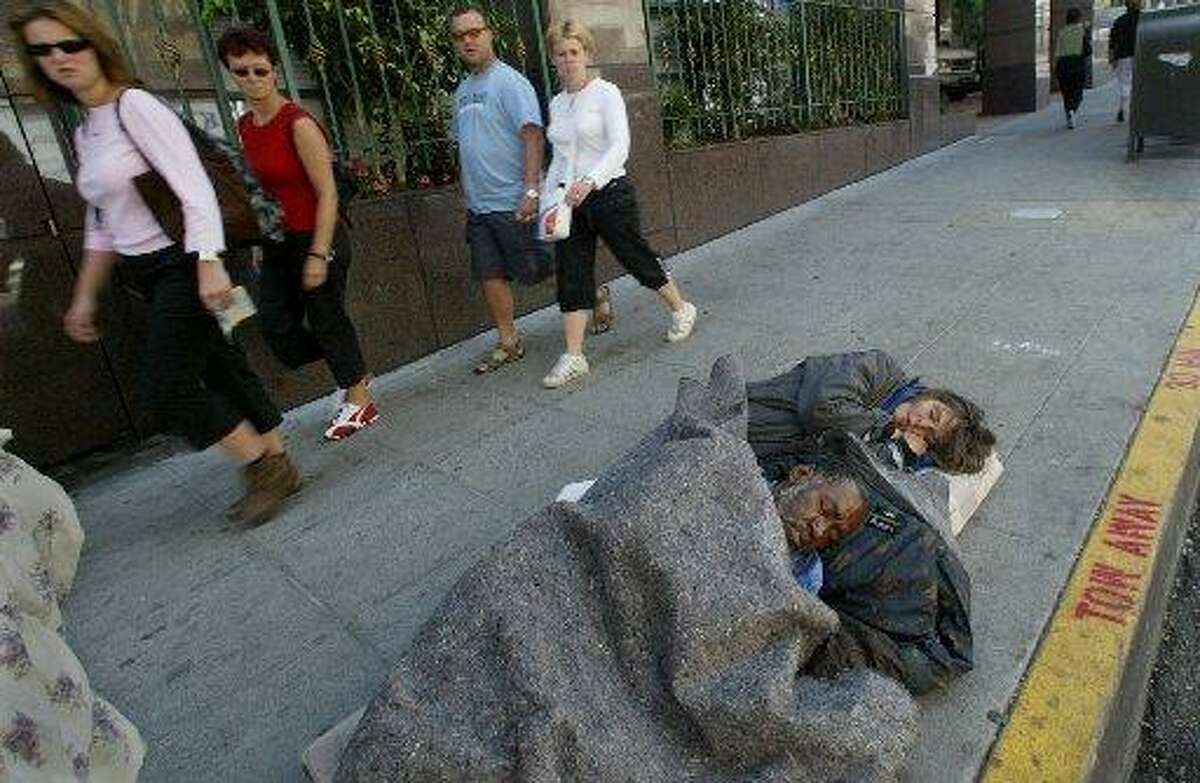 Tourists walk past a man people sleeping on Ellis Street in S.F.
