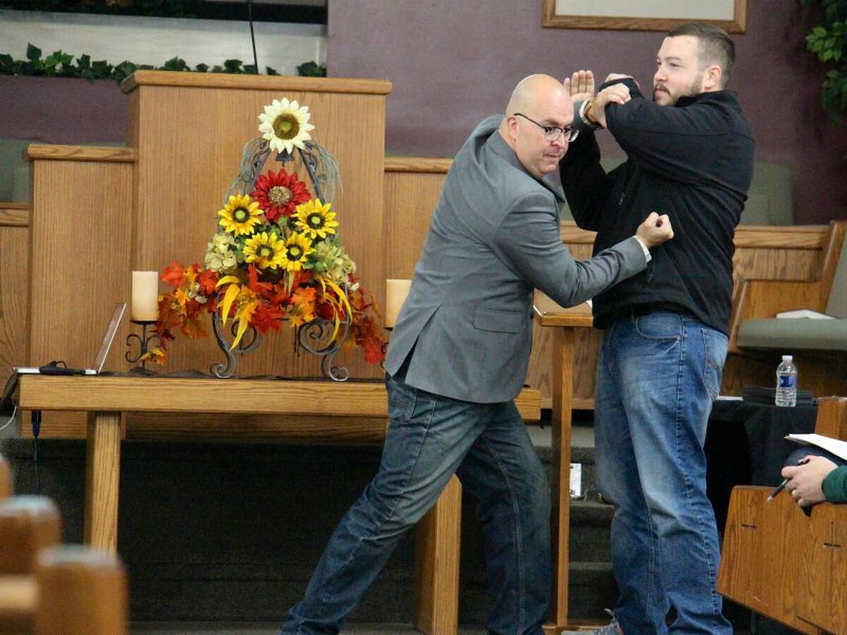 Barry Young, vice president of Church Security Ministries at Strategos, demonstrates using a tactical pen for self-defense on Marc Anderson at an intruder awareness and response training session at Prairie Baptist Church in Scotts, Mich.