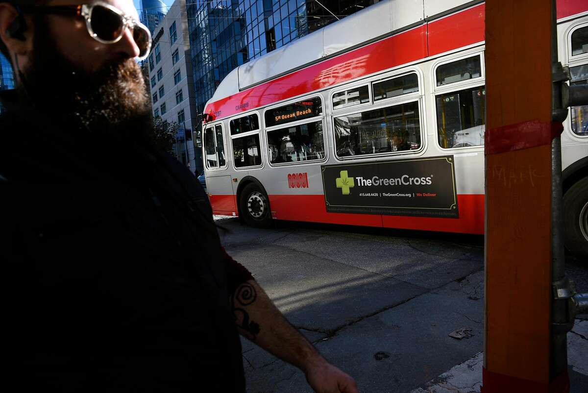 A pedestrian walks past an advertisement for The Green Cross marijuana dispensary is seen on the side of a MUNI bus in downtown San Francisco, CA, on Friday November 17, 2017.