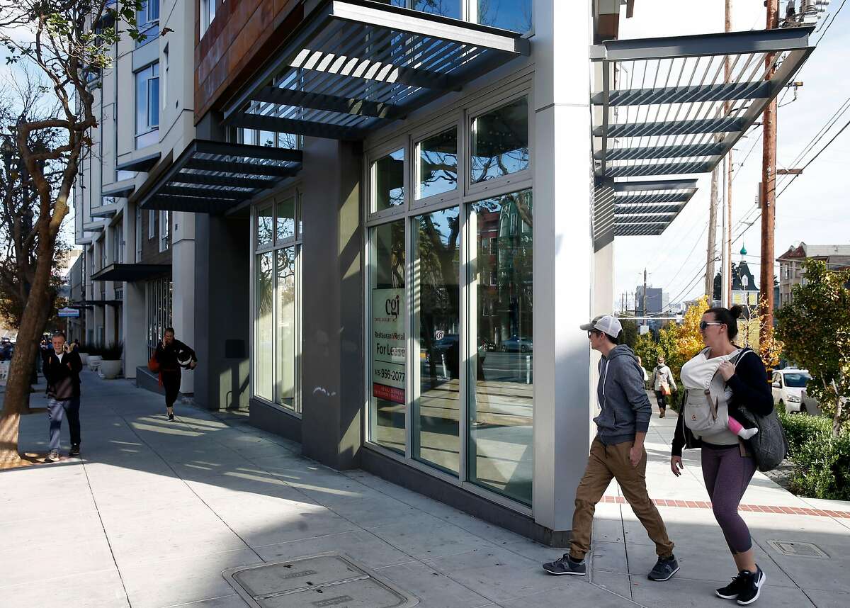 People walk past a vacant restaurant space on a corner location of a new residential building at Market and 15th streets in San Francisco, Calif. on Saturday, Nov. 11, 2017.