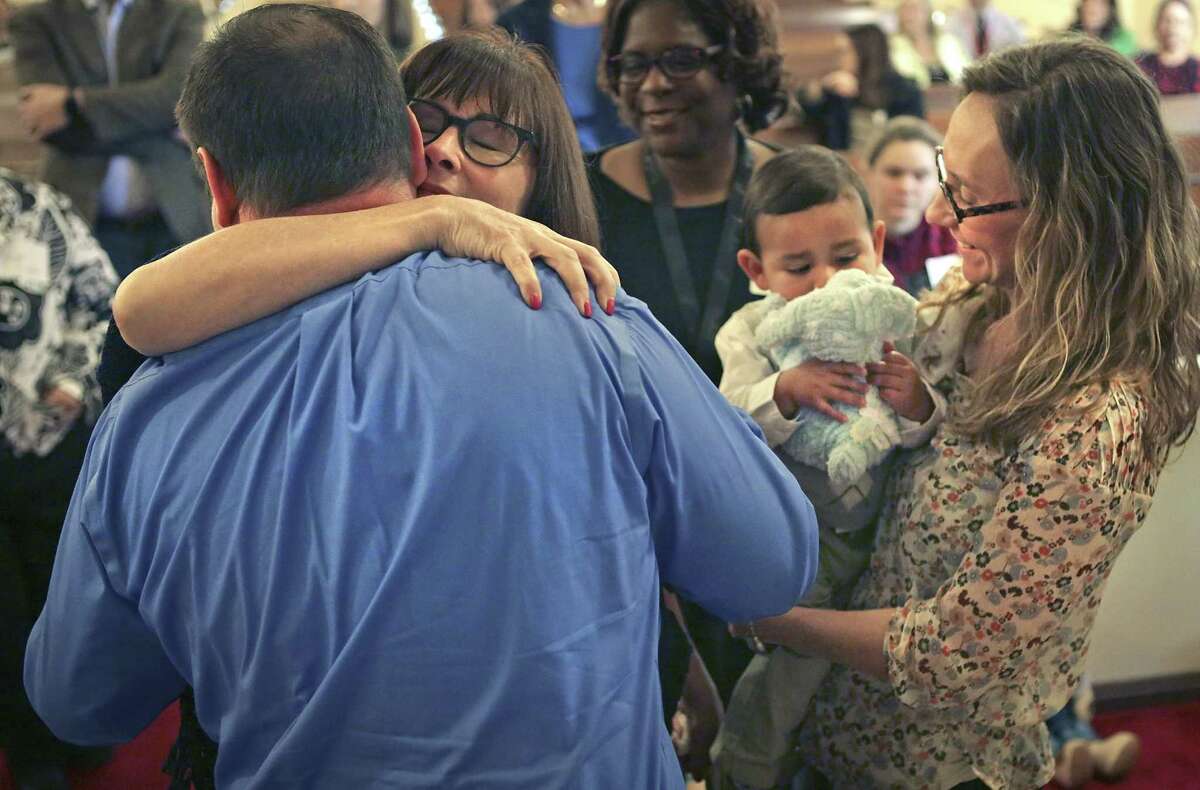 Donna Couch hugs her son, Clint Walker (left), as his wife, Karen Walker, holds one of the couple’s two adopted sons, 19-month-old Antonio Walker. The Walkers formally adopted the two boys Monday at a Texas Department of Family and Protective Services adoption day ceremony at the First Presbyterian Church in Seguin. The family lives in San Antonio.