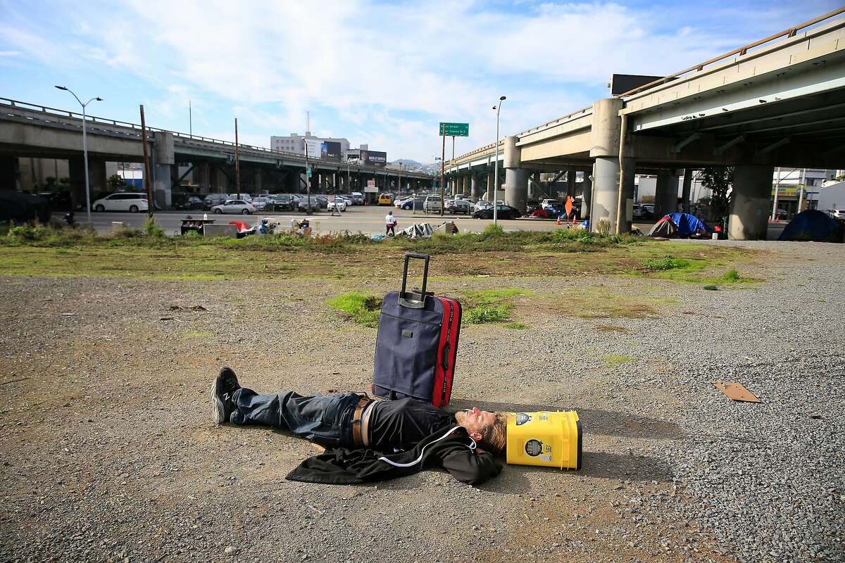 Shane Peak, 35, who says he has been dealing with homelessness on and off for 8 years, catches some rest as he lays on a patch of ground along Fifth Street below Interstate 80 on Tuesday, November 21, 2017 in San Francisco, Calif.