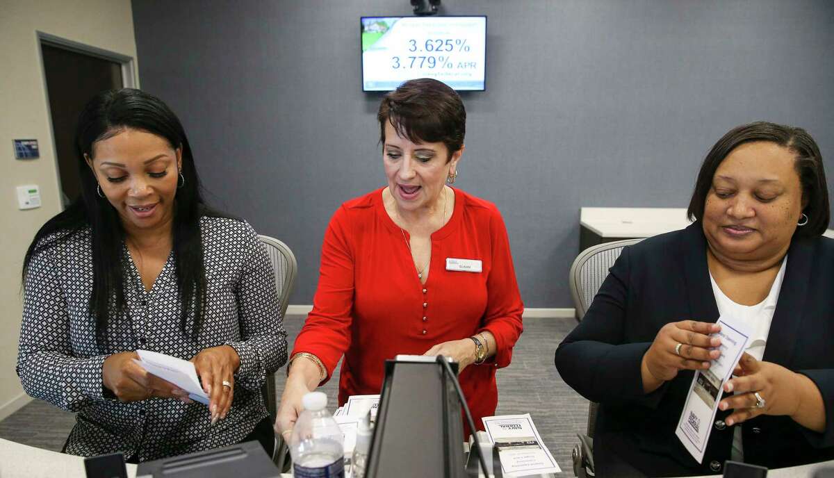 Navy Federal Credit Union branch manager Susan Simmons, center, and tellers Shawntay Hagan, left, and Marie Johnson fold pamphlets as they prepare for ﻿their branch's grand opening in Sugar Land. ﻿
