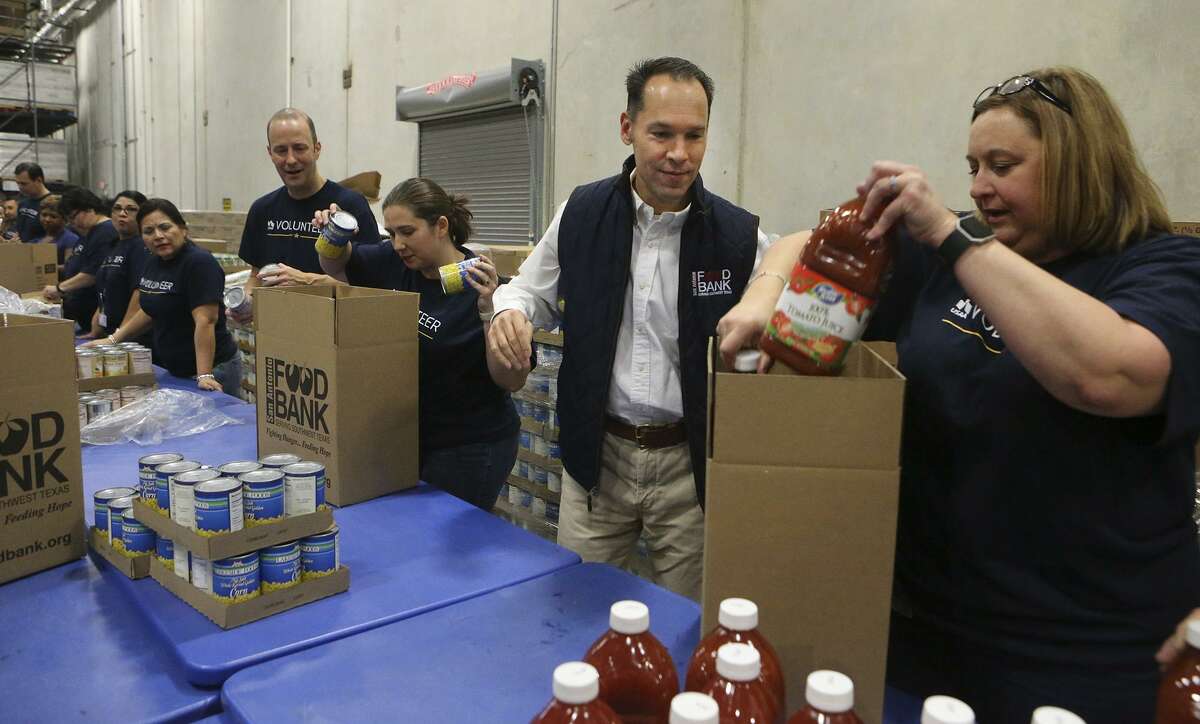 Eric S. Cooper, (second from right) CEO of the San Antonio Food Bank, packs boxes of food for seniors with volunteers from USAA at the San Antonio Food Bank. According to Cooper, the Food Bank serves 16 counties in the San Antonio area. The San Antonio Food Bank is on a 40-acre campus and has about 200 employees.