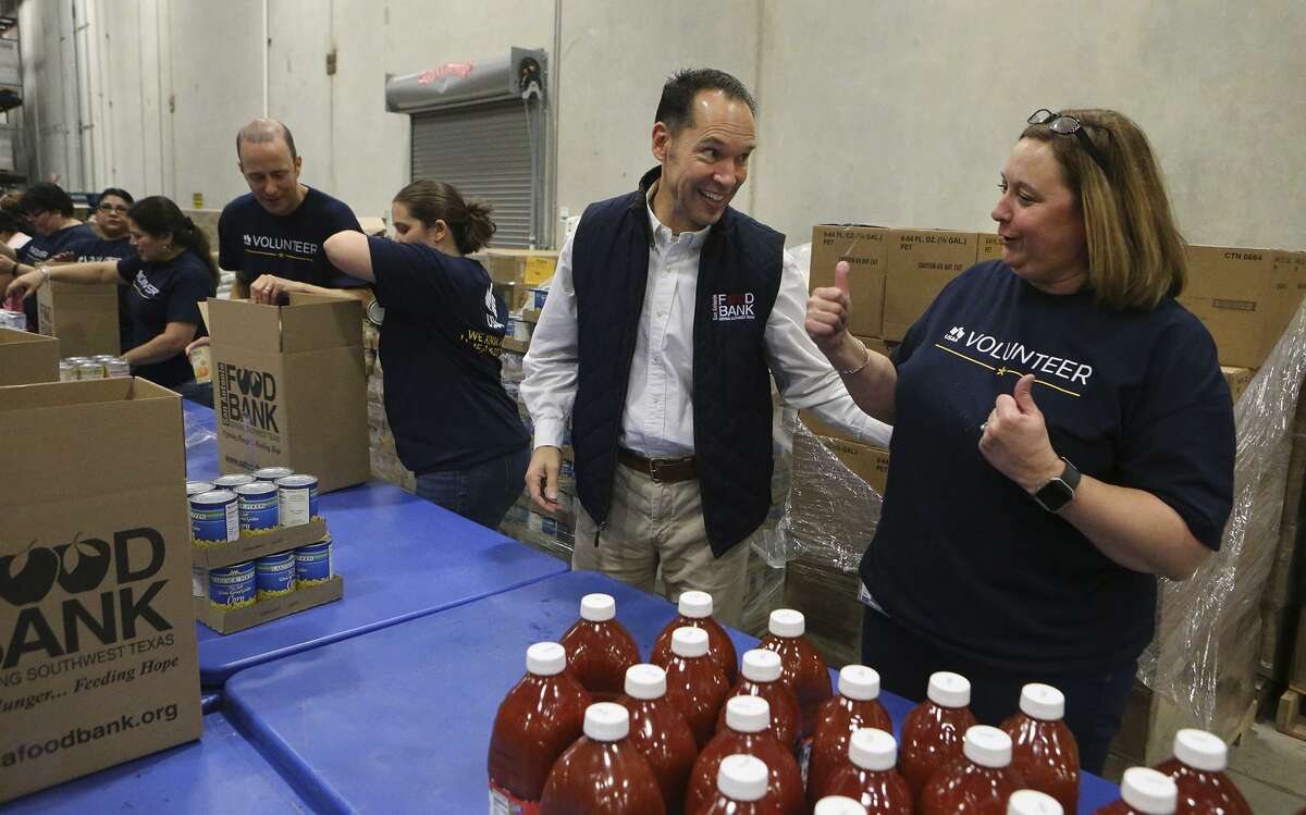 Eric S. Cooper, (second from right) CEO of the San Antonio Food Bank, packs boxes of food for seniors with volunteers from USAA at the San Antonio Food Bank. According to Cooper, the Food Bank serves 16 counties in the San Antonio area. The Food Bank is on a 40 acre campus and has about 200 employees. On the right is USAA volunteer Molly Spears.
