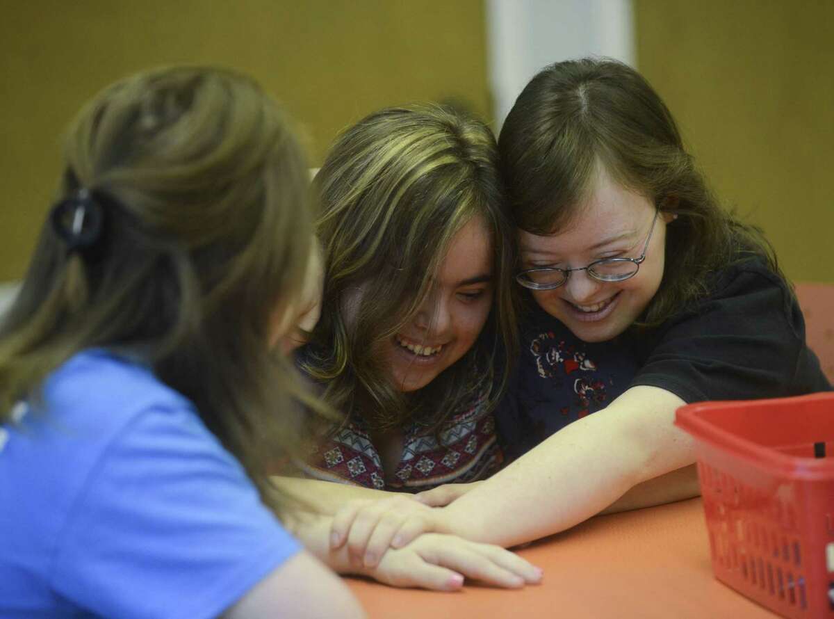 Mallory Cohn (center) and Gilver embrace as they start their day at SA Life Academy. The organization provides a day curriculum and field trips for adults with disabilities.