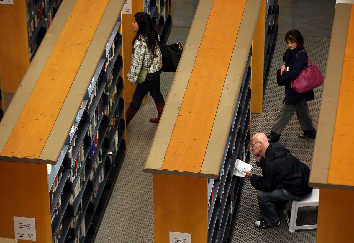 2011年1月11日，加利福尼亚州旧金山市，一名图书馆顾客在旧金山公共图书馆的主分馆看书。图书馆正在从疫情的冬眠中苏醒，主图书馆和精进分馆应该在8月初开放，以便在路边领取预订的书籍。