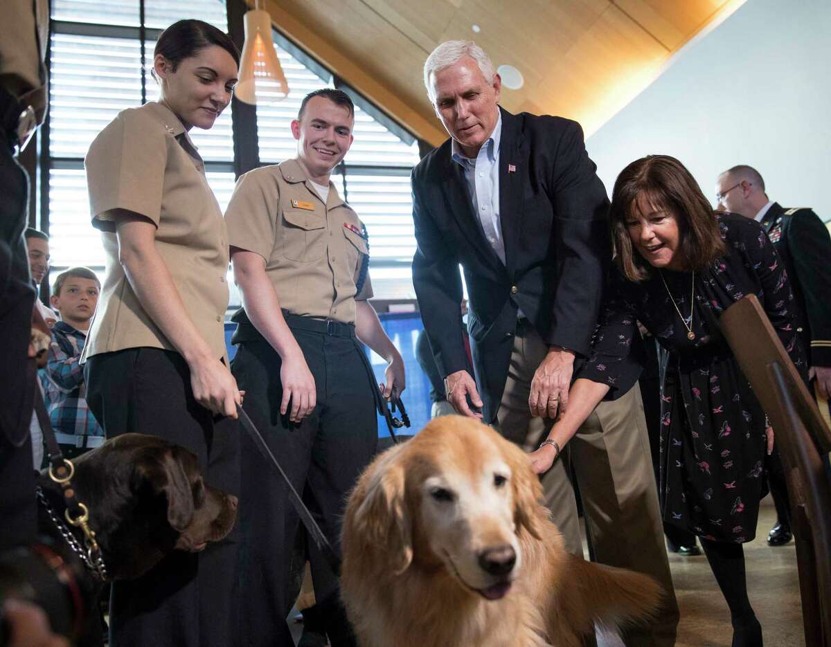 Vice President Mike Pence and his wife Karen Pence pet facility dogs Goldie, right, and Truman, left, as they visit patients and their families and care providers at the USO Warrior and Family Center at Walter Reed National Military Medical Center in Bethesda, Md., Wednesday, Nov. 22, 2017. (AP Photo/Carolyn Kaster)