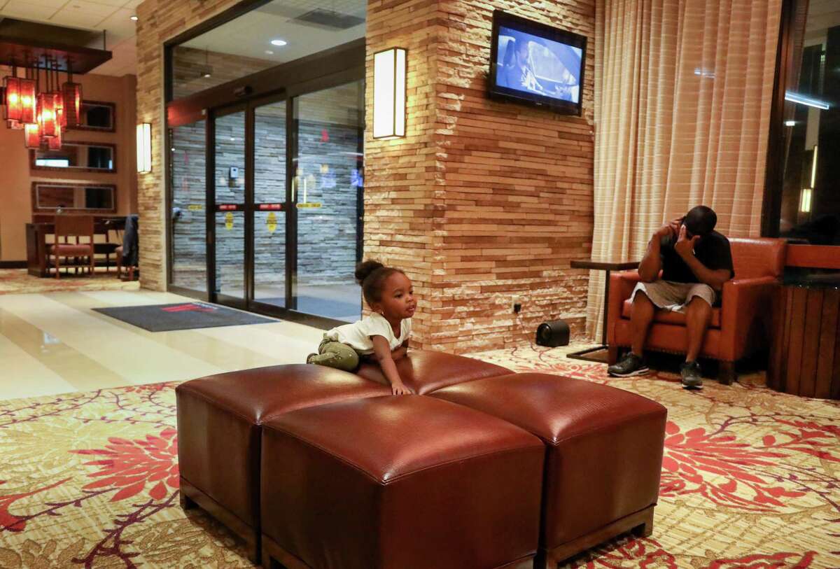 Nori Nolan, 3, plays in the lobby of a hotel in the Greenspoint area, while her mother's boyfriend, Mikey Robinson, right, talks on the phone, Wednesday, Nov. 15, 2017, in Houston.
