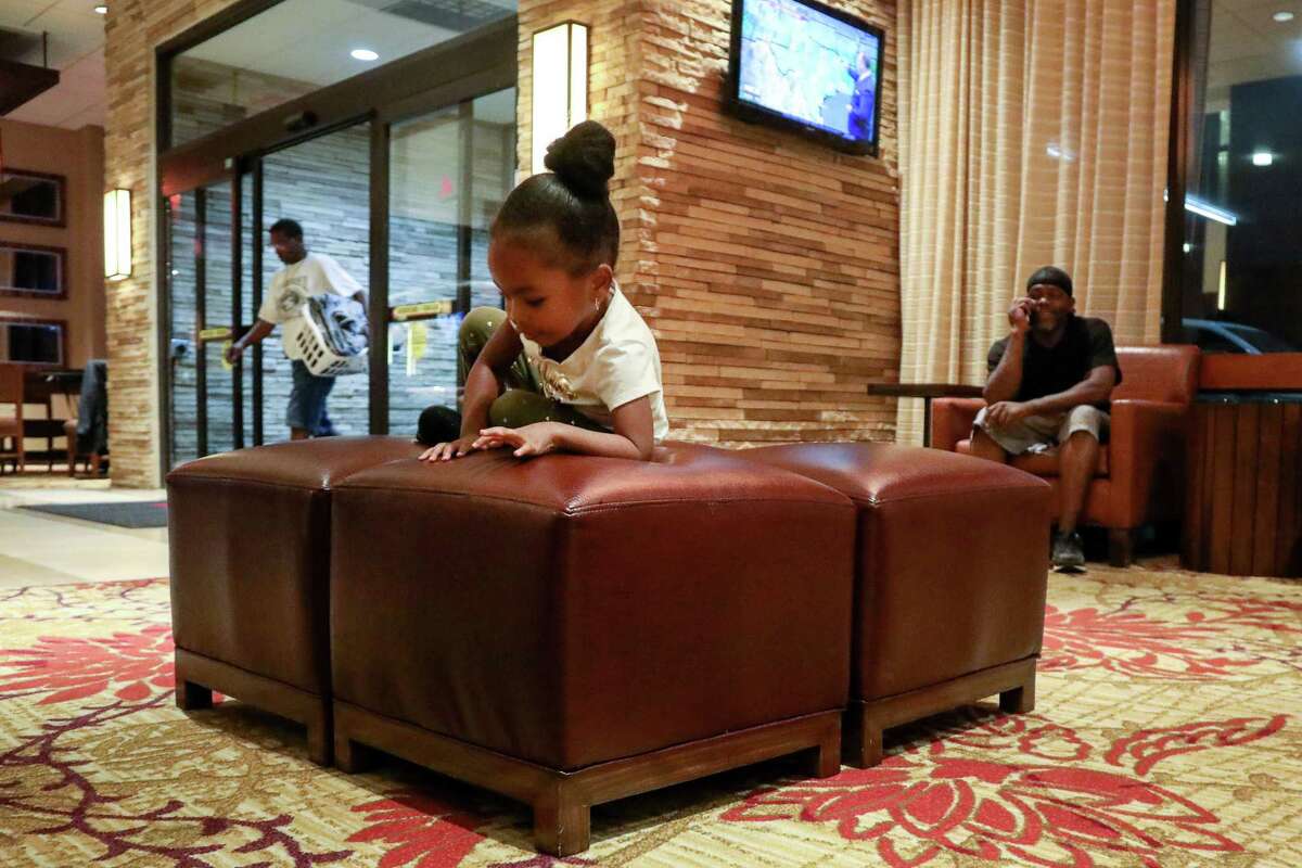 Nori Nolan, 3, plays in the lobby of a hotel in the Greenspoint area, while her mother's boyfriend, Mikey Robinson, right, talks on the phone, Wednesday, Nov. 15, 2017, in Houston. ( Jon Shapley / Houston Chronicle )