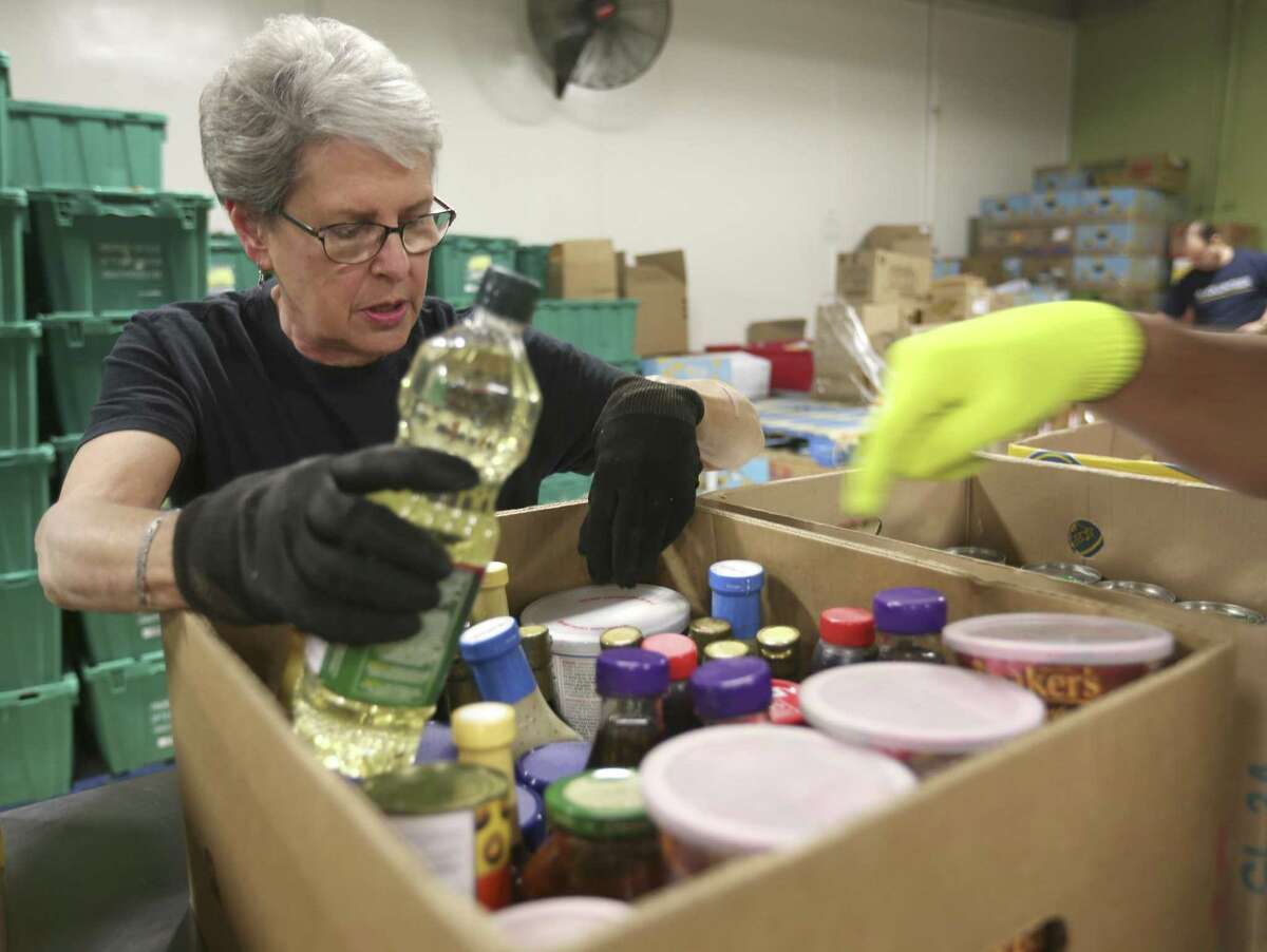 Janet McDaniel, a member of the Apple Corps volunteer group at the San Antonio Food Bank, sorts donated food. She said the work is about more than giving back.