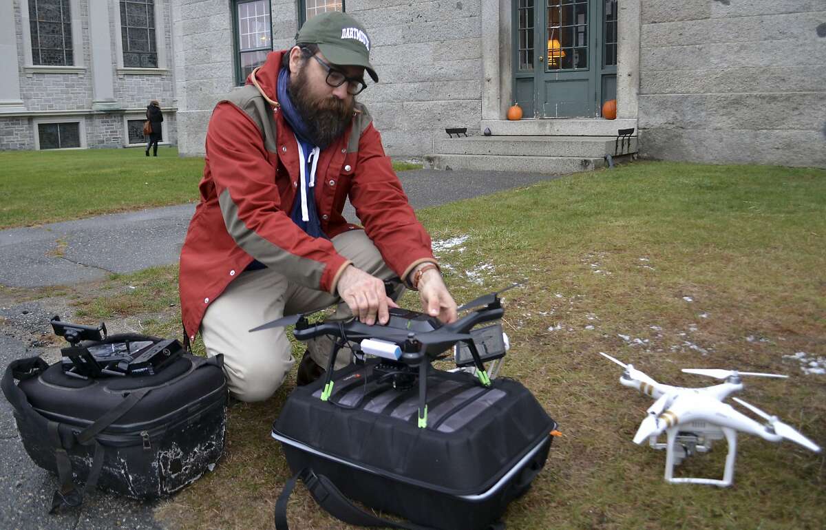 In this Nov. 14, 2017, photo, Dartmouth's Chad Hill readies a drone to be flown over a site of a Shaker Village in Enfield, NH. Hill and his Dartmouth colleague Jesse Casana are using drones equipped with thermal imaging cameras to study a half-dozen archaeological sites around the world. The cameras use heat differences between stone and the soil surrounding it to identify structures below the surface like foundations of buildings, which then can be further explored. (AP Photo/Michael Casey)