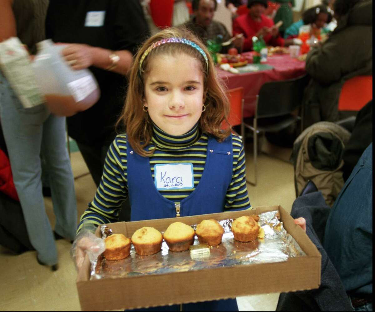 Kara Ferraro, 8, serves corn muffins to the clients at the Thanksgiving Day dinner at the New Covenant House of Hospitality on West Main Street in Stamford on Nov. 27, 1997. She was one of the volunteers from the St. Leo parish.