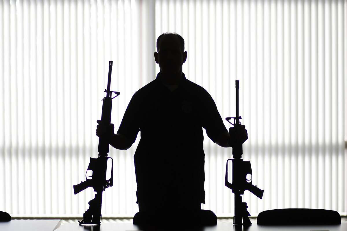 FILE - In this Aug. 29, 2017, file photo, an ATF agent poses with homemade rifles, or 'ghost guns,' at an ATF field office in Glendale, Calif. A gun control group founded by former U.S. Rep. Gabby Giffords asked two web hosting companies on Friday, Nov. 24, 2017, to shut down websites selling parts and machines that help make untraceable homemade firearms known as �ghost guns.� The Giffords Law Center to Prevent Gun Violence asked the providers that host GhostGunner.net and GhostGuns.com to disable the websites for violating the hosting companies� terms of service. (AP Photo/Jae C. Hong, File)