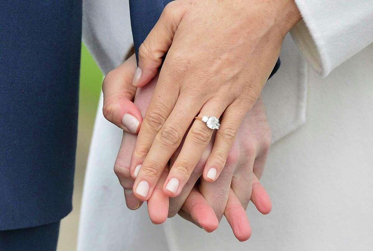 Meghan Markle wears her engagement ring as she poses with Britain's Prince Harry for the media in the grounds of Kensington Palace in London, Monday Nov. 27, 2017. It was announced Monday that Prince Harry, fifth in line for the British throne, will marry American actress Meghan Markle in the spring, confirming months of rumors. (Dominic Lipinski/PA via AP)