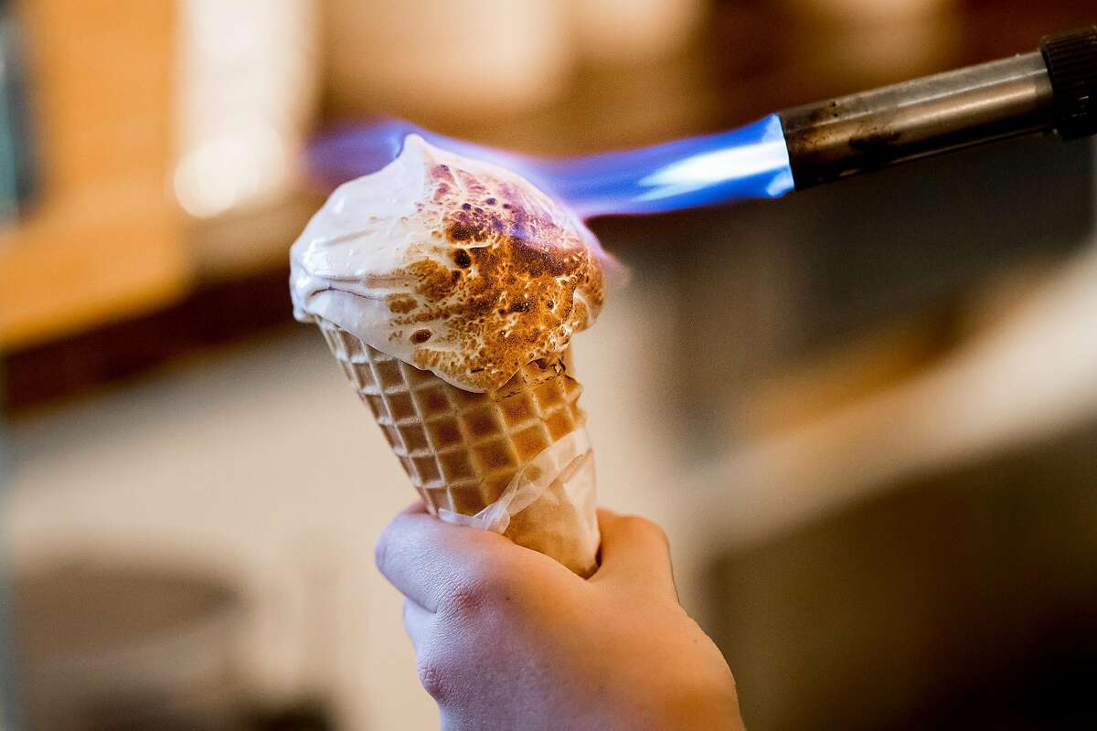 A worker uses a torch to make toasted marshmallow fluff atop a waffle cone at The Penny Ice Creamery on Saturday, Nov. 18, 2017, in Santa Cruz, Calif.