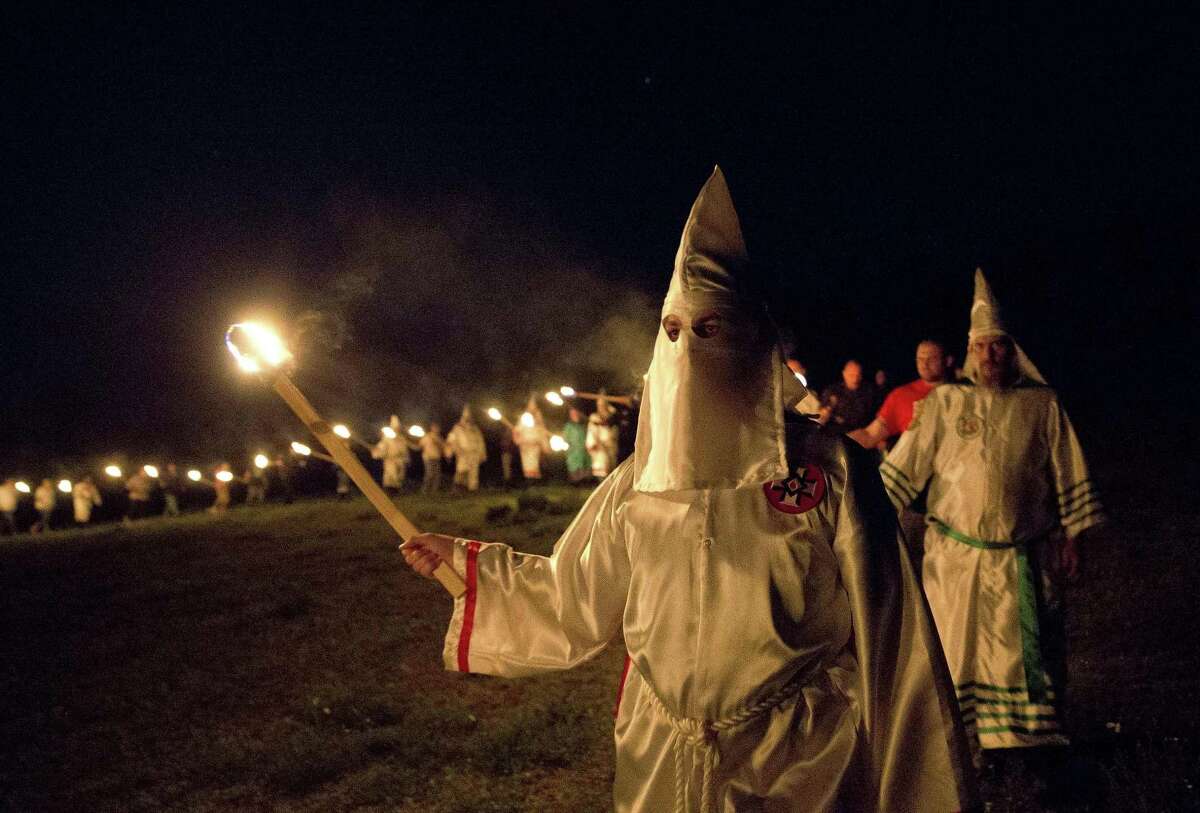 In this Saturday, April 23, 2016, photo, members of the Ku Klux Klan participate in cross burnings after a "white pride" rally in rural Paulding County near Cedar Town, Ga. Born in the ashes of the smoldering South after the Civil War, the KKK died and was reborn before losing the fight against civil rights in the 1960s. Membership dwindled, a unified group fractured, and one-time members went to prison for a string of murderous attacks against blacks. Many assumed the group was dead, a white-robed ghost of hate and violence.