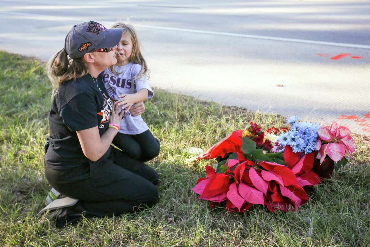 Ashley Axelson consoles her daughter Riley, 4, on Monday after she left flowers at an impromptu memorial for ASI Gymnastics coach Mike DeLuke off of FM 1488. Riley was one of DeLuke's more than 130 students at The Woodlands-based gymnasium.