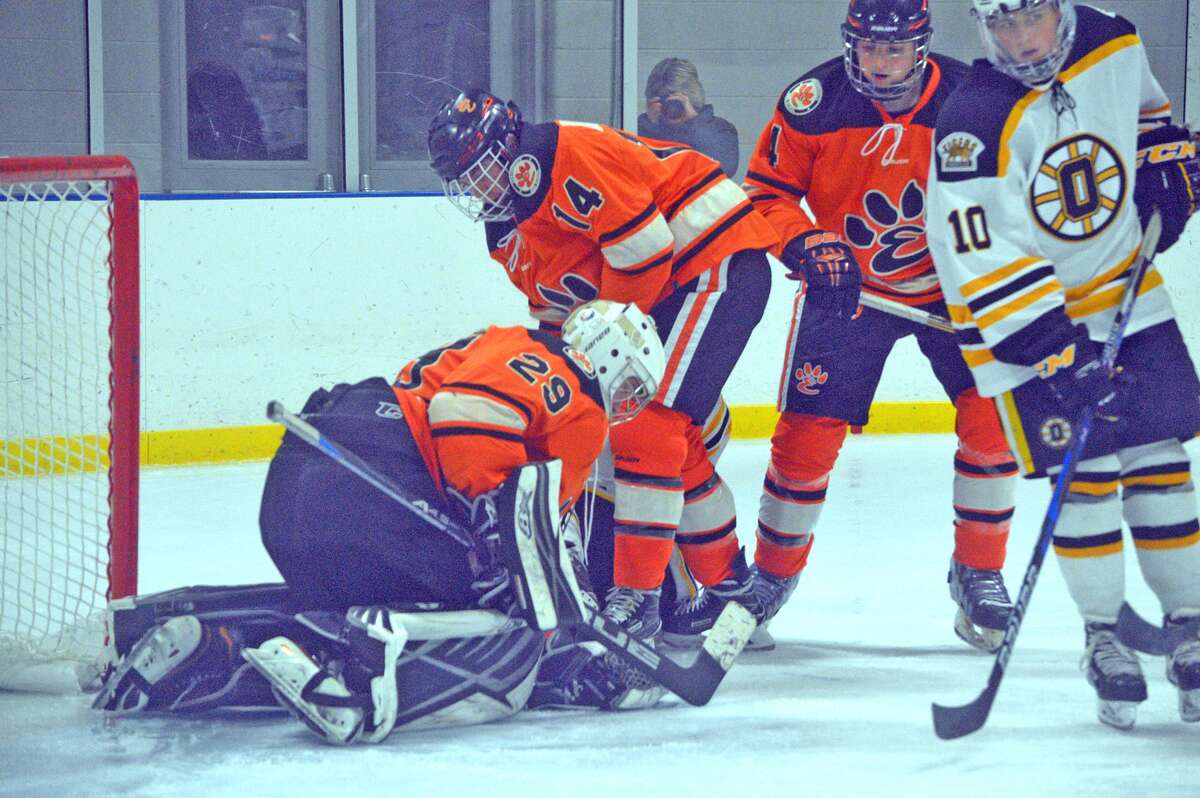 Edwardsville goalie Matthew Griffin, left, with help from defenseman Trevor Laub, covers up the puck during the first period of Monday’s game against Oakville.