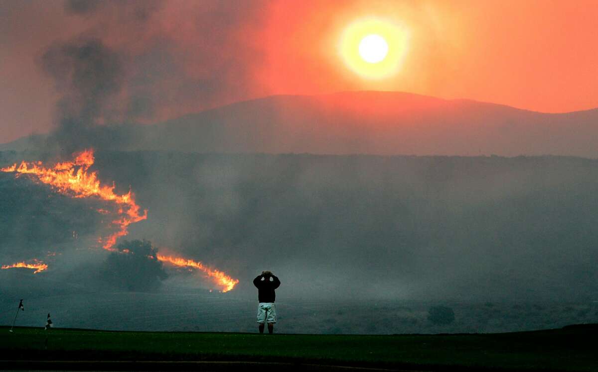 Flames advance near Chula Vista in San Diego County during a devastating series of wildfires in 2007. San Diego Gas & Electric Co., whose equipment helped spark the wind-driven fires, wants its customers to pay some of the costs of lawsuits that followed the flames.