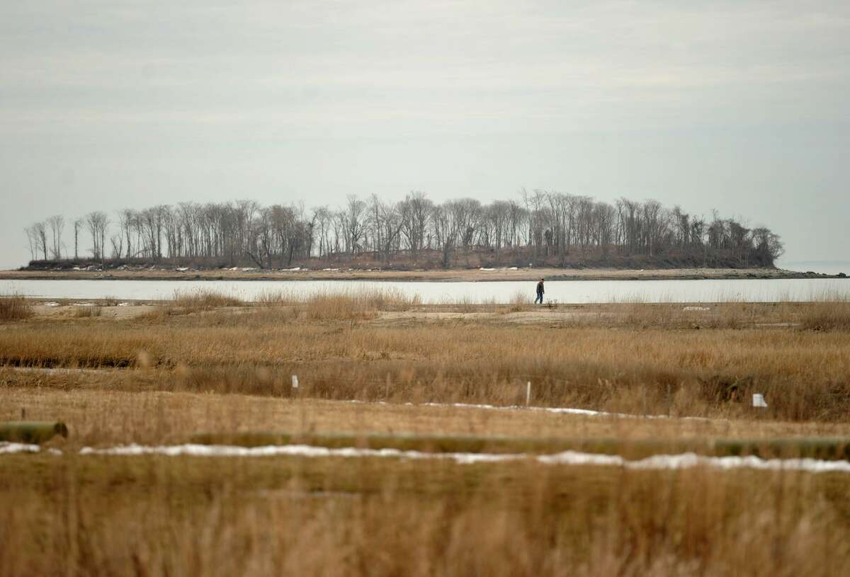 A man walks the boardwalk at Silver Sands State Park in Milford earlier this year.