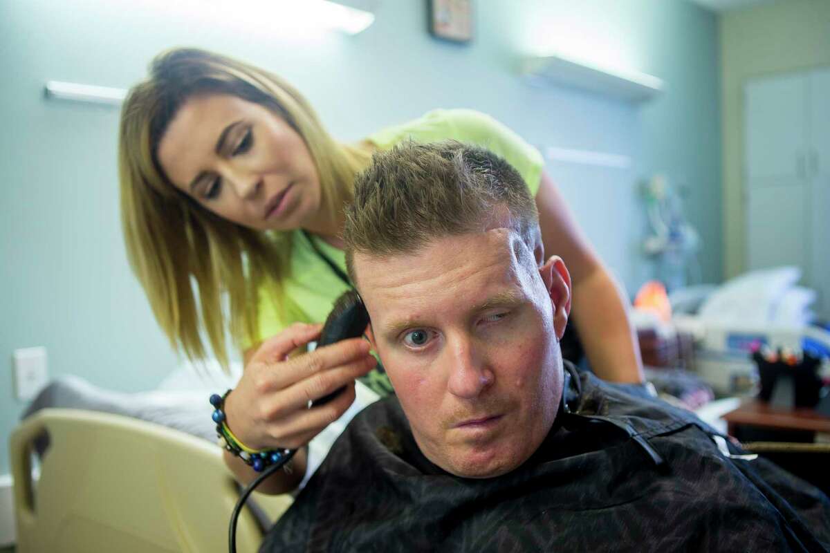 Danielle McNicoll trims fiancé Nick Tullier's hair in his room at TIRR Memorial Hermann.