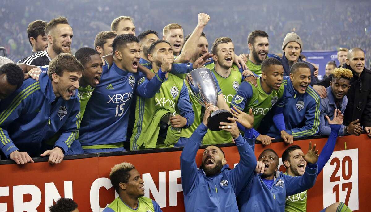 Seattle Sounders' Clint Dempsey holds the championship trophy up as teammates cheer around him after the Sounders defeated the Houston Dynamo 3-0 in the second leg of the MLS soccer Western Conference final, Thursday, Nov. 30, 2017, in Seattle. The Sounders advanced to the MLS Cup. (AP Photo/Elaine Thompson)