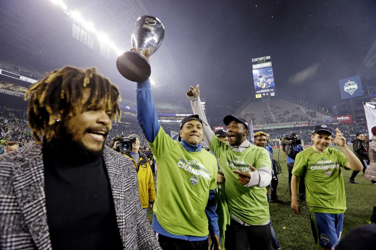 Seattle Sounders players cheer as one holds the conference trophy after the Sounders defeated the Houston Dynamo 3-0 in the second leg of the MLS soccer Western Conference final, Thursday, Nov. 30, 2017, in Seattle. The Sounders won an aggregate and advanced to the MLS Cup. (AP Photo/Elaine Thompson)