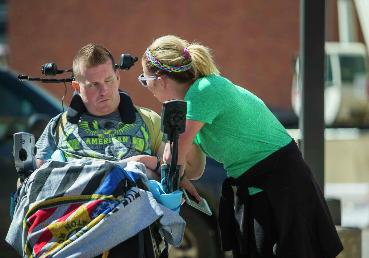 Danielle encourages Nick, who seems inattentive, to keep working with his motorized wheelchair in the TIRR Memorial Hermann parking lot.