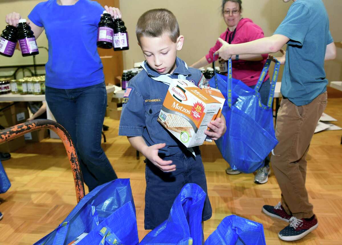 (Arnold Gold-New Haven Register) Seth Glassman, 9, of Cub Scout Pack 923 in Orange places boxes of matzo into kosher for Passover food packages for some of over 380 area families at the Jewish Community Center of Greater New Haven in Woodbridge on 4/17/2016. B'nai B'rith International organizes Project H.O.P.E., Help Our People Everywhere, to deliver Passover food to poor and elderly Jews at Passover in several Northeastern states.