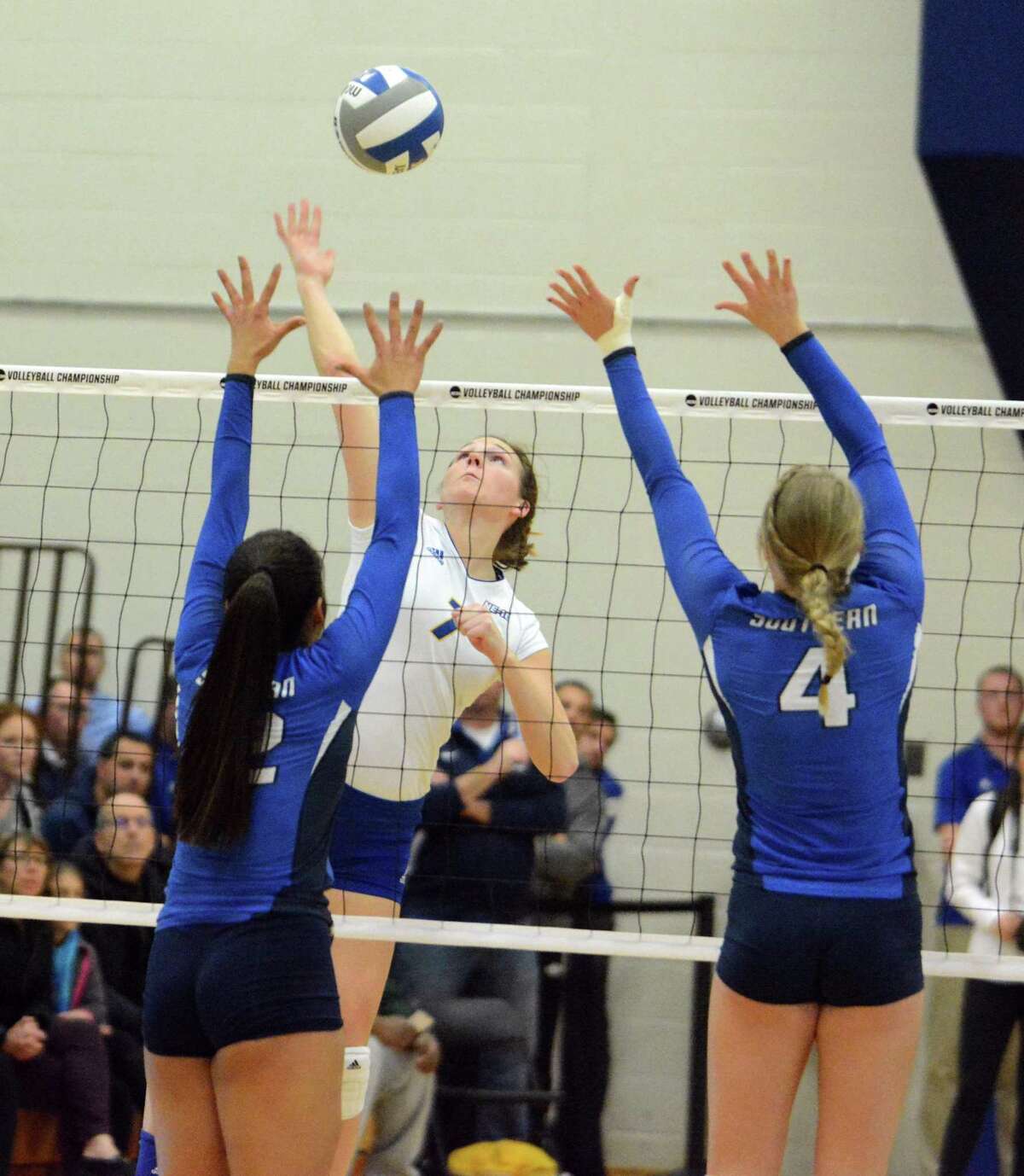 New Haven's Mallory Nowicki hits the ball as SCSU's Leanna Jadus, left, and Alyssa Gage defend on Friday.