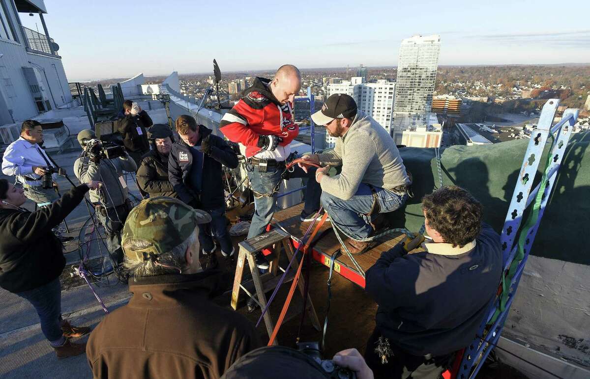 Ron Markey with the City of Stamford and will portray Rudolf does a safety check prior to Brian Cashman, General Manager of the New York Yankees rappel off the Landmark building on Friday, Dec. 1, 2017 in Stamford, Connecticut. Cashman, along with Duke Castiglione, FOX 5 Sports Anchor and Todd Piro, FOX News Channel's Correspondent, were taking practice runs in preparation for Stamford's Heights & Lights program on Sunday.