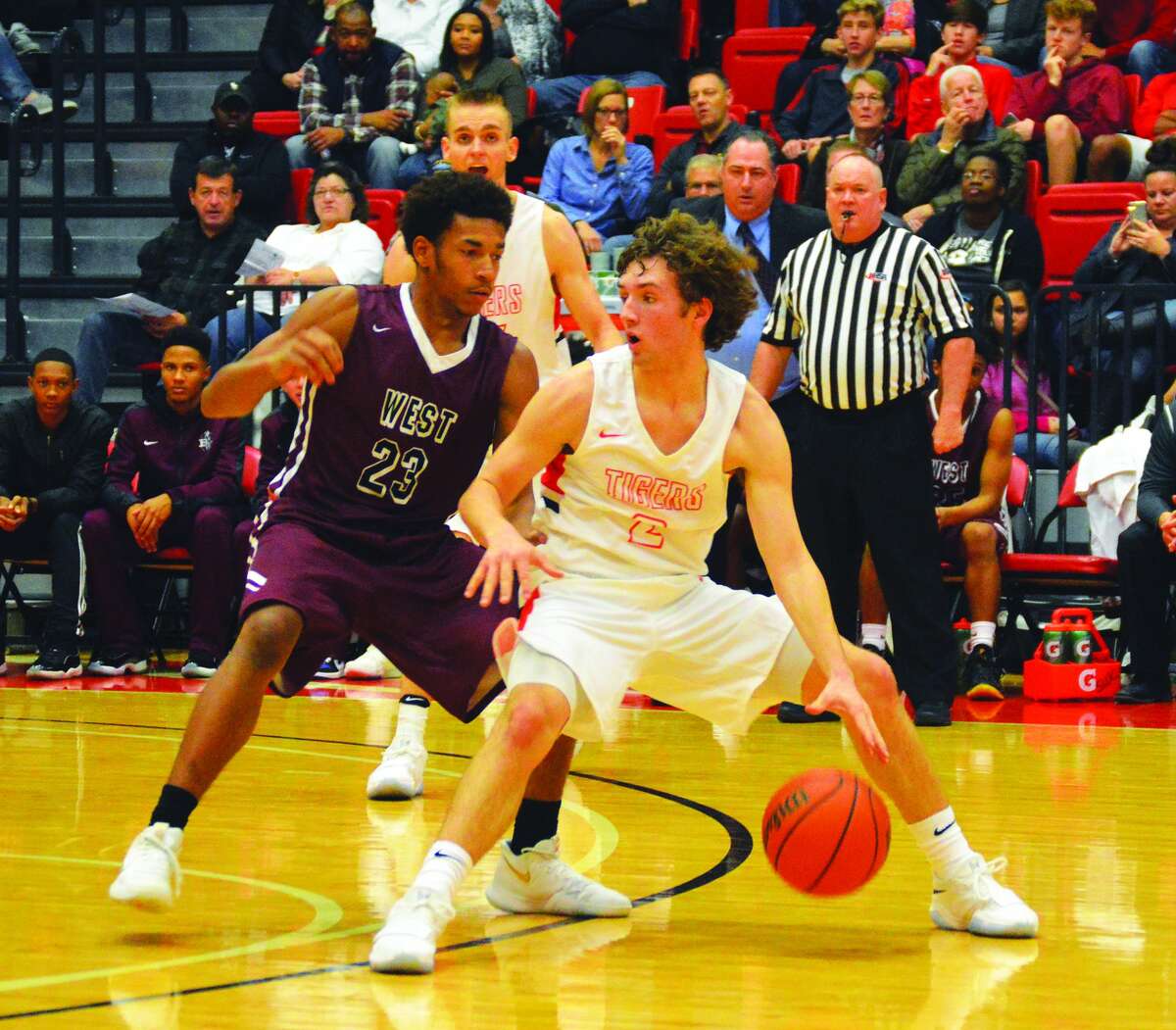 Edwardsville guard Jack Marinko, right, dribbles the ball away from Belleville West’s Curtis Williams during first-half action inside the Vadalabene Center on the campus of SIUE.