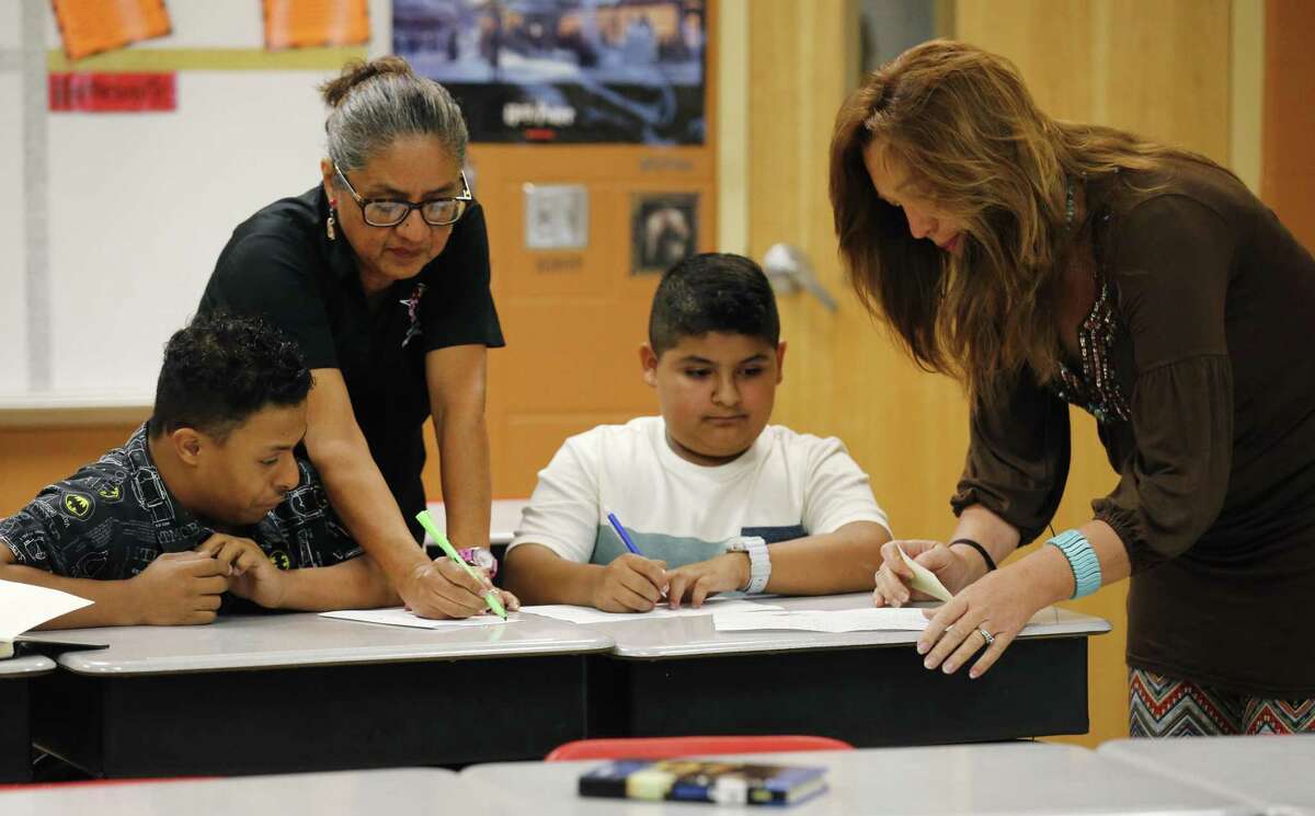 Markus Davis (from left), 12, receives help from teacher's aide Lesa Beth Rodriguez, fellow sixth-grader Elijah Cantu and substitute teacher Heather Baker in class on Thursday, Nov. 16, 2017. Davis is deaf and entered Losoya Intermediate School in Southside ISD last year without any friends. But this year Cantu was assigned to help him. Markus taught Elijah sign language and, according to the school principal, Elijah brought Markus out of his shell. (Kin Man Hui/San Antonio Express-News)