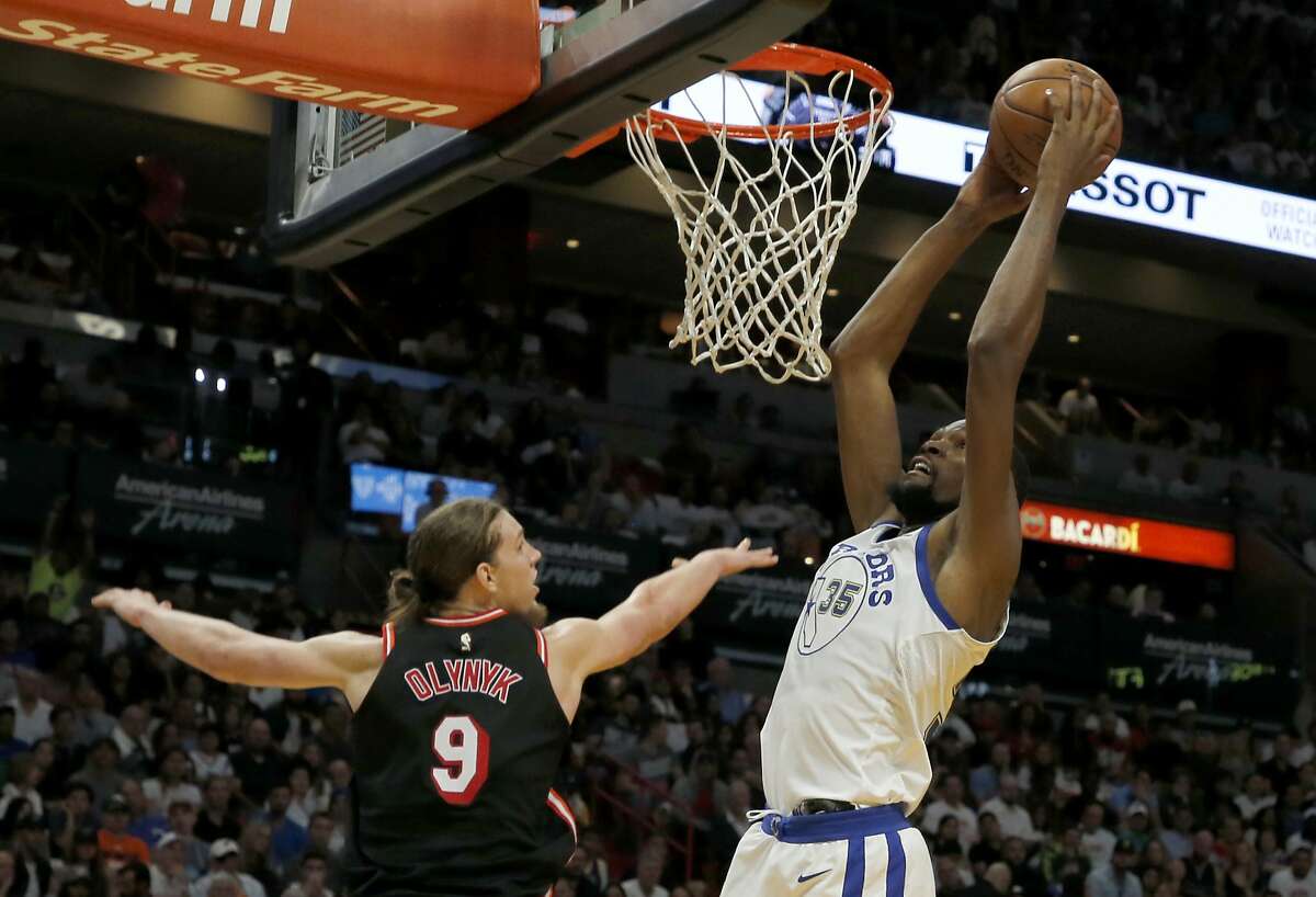 Golden State Warriors forward Kevin Durant (35) dunks next to Miami Heat center Kelly Olynyk during the first quarter of an NBA basketball game, Sunday, Dec. 3, 2017, in Miami. (AP Photo/Joe Skipper)
